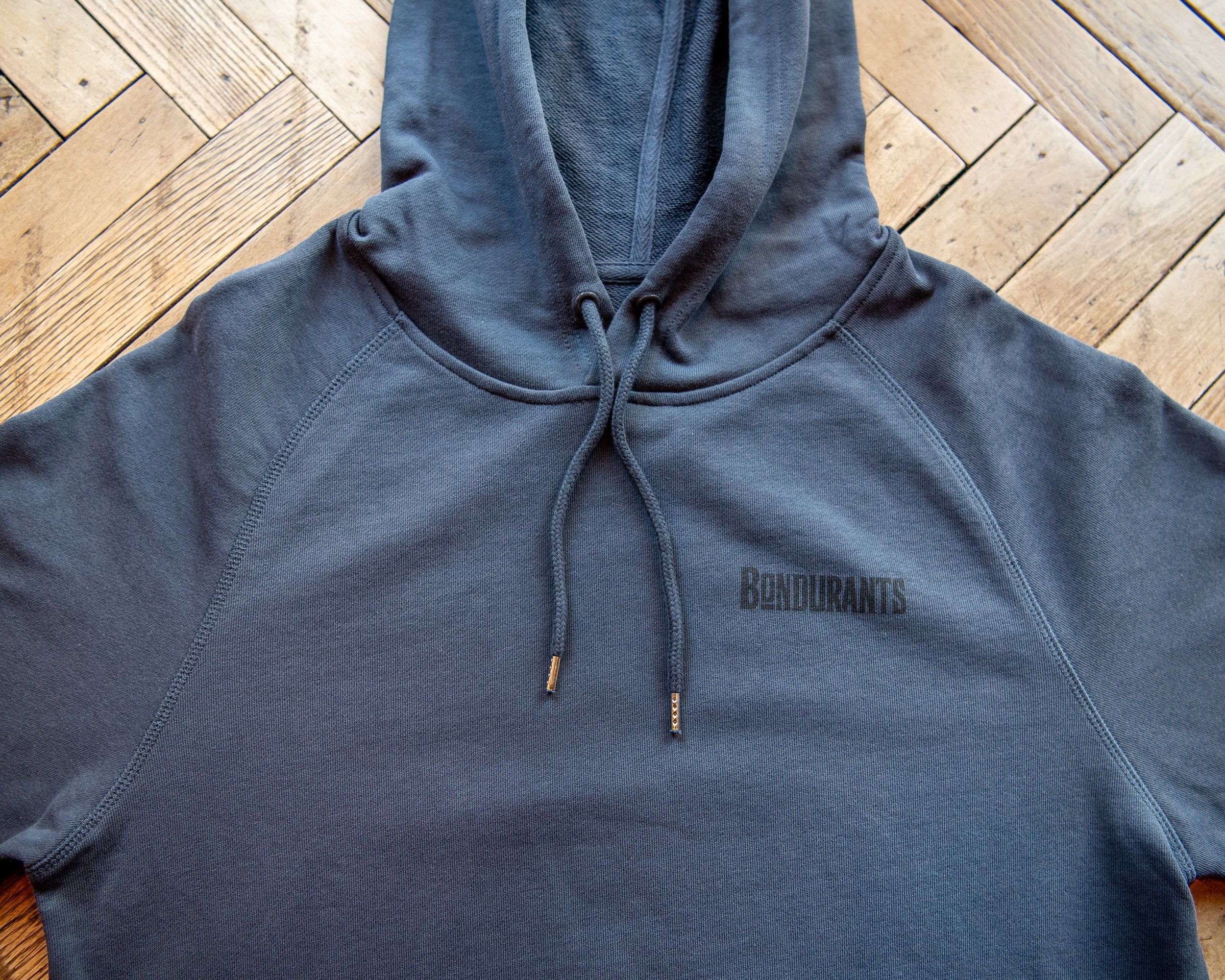 Blue hoodie with 'Bendurants' branding on a wooden floor