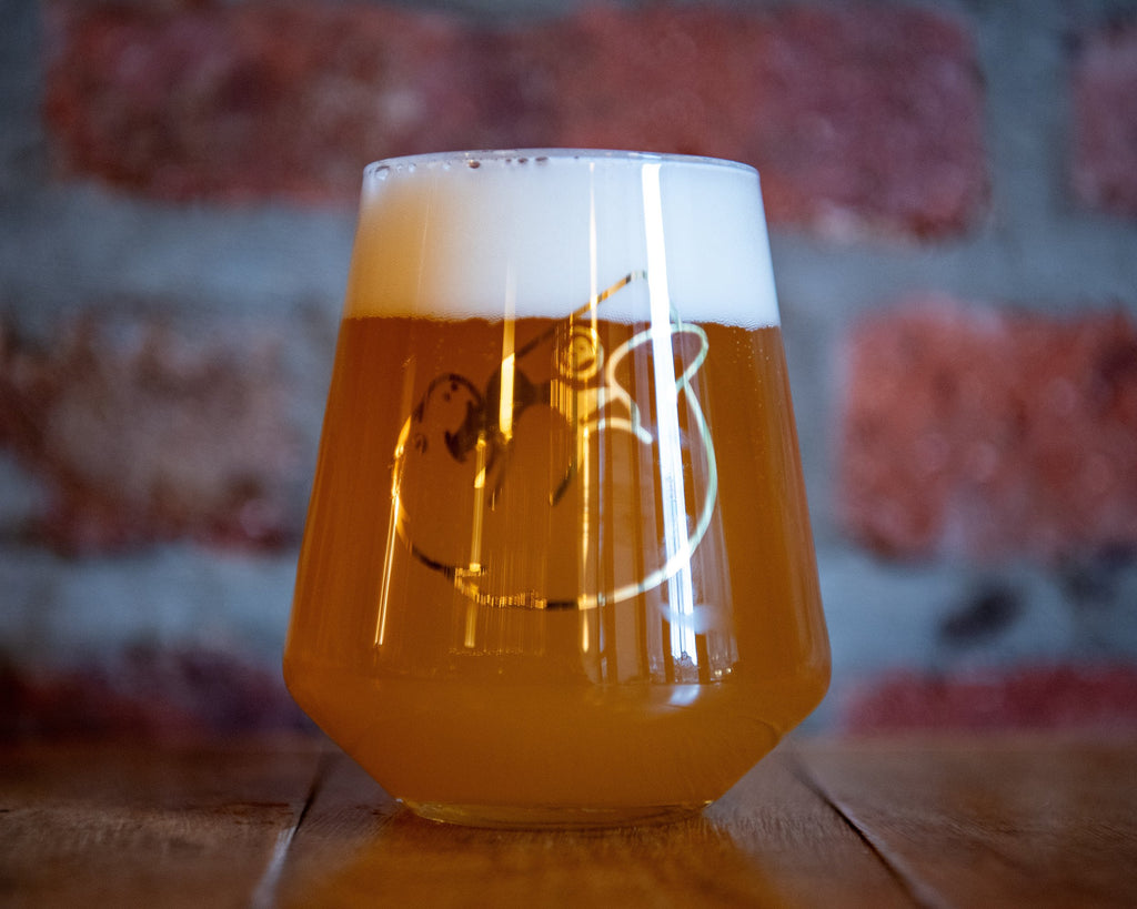 Glass of beer with a logo on a wooden surface and blurred background
